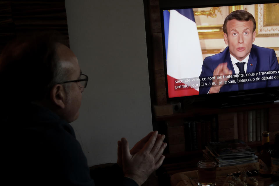 Giuseppe Fonsino, listens to the speech of French President Emmanuel Macron on TV, in Ville d'Avray, near Paris, Monday, April 13, 2020. Macron said that the country's coronavirus lockdown will be extended till May 11. The new coronavirus causes mild or moderate symptoms for most people, but for some, especially older adults and people with existing health problems, it can cause more severe illness or death. (AP Photo/Christophe Ena)