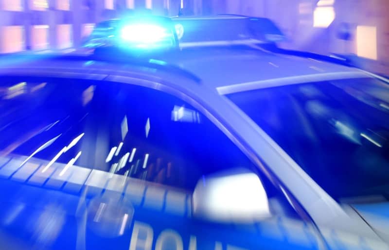 A police patrol car is parked on the street with its blue lights switched on. Unidentified perpetrators have thrown stones and an incendiary device at the residence of a far-right city councillor in the eastern German city of Halle, police said on Monday morning, in yet another attack targeting a politician in the country. Carsten Rehder/dpa