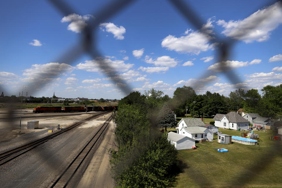 A freight train yard is separated from a neighborhood by a row of trees, Tuesday, June 15, 2021, in Galesburg, Ill. Settled more than 180 years ago, Galesburg was built around Knox College, founded by Presbyterians from upstate New York seeking a Christian school on the western frontier. The city soon became home to Illinois' first anti-slavery society. (AP Photo/Shafkat Anowar)