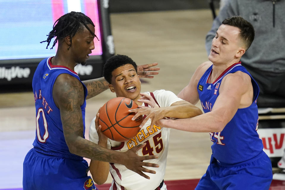 Iowa State guard Rasir Bolton, center, looks to pass between Kansas guard Marcus Garrett, left, and forward Mitch Lightfoot, right, during the second half of an NCAA college basketball game, Saturday, Feb. 13, 2021, in Ames, Iowa. Kansas won 64-50. (AP Photo/Charlie Neibergall)