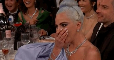 Lady Gaga covering her mouth and laughing at the Golden Globe Awards