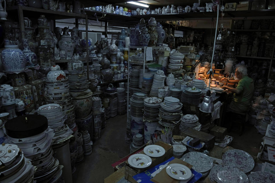 A staff member works at the Yuet Tung China Works, Hong Kong's porcelain factory, in Hong Kong, Wednesday, June 8, 2022. Step into Yuet Tung China Works, Hong Kong’s last remaining hand-painted porcelain factory, and you find yourself surrounded by stacks of dinnerware, each piece painstakingly decorated by hand with vibrant motifs of flowers, fruits and animals.(AP Photo/Kin Cheung)