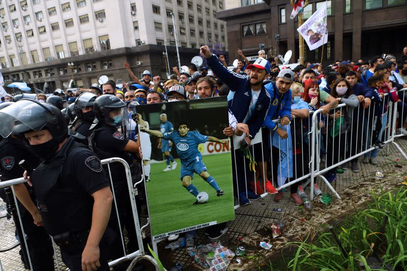 People react while lining up for the wake of soccer legend Diego Maradona at the presidential palace Casa Rosada, in Buenos Aires