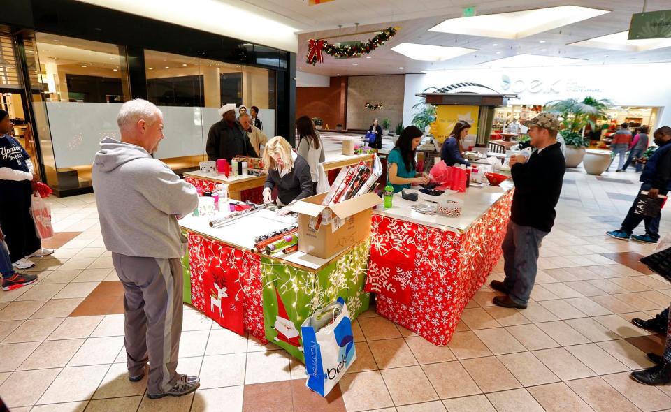 Employees of All Wrapped Up wrap presents for last minute shoppers on Christmas Eve at University Mall Wednesday, Dec. 24, 2014. [Staff file photo]