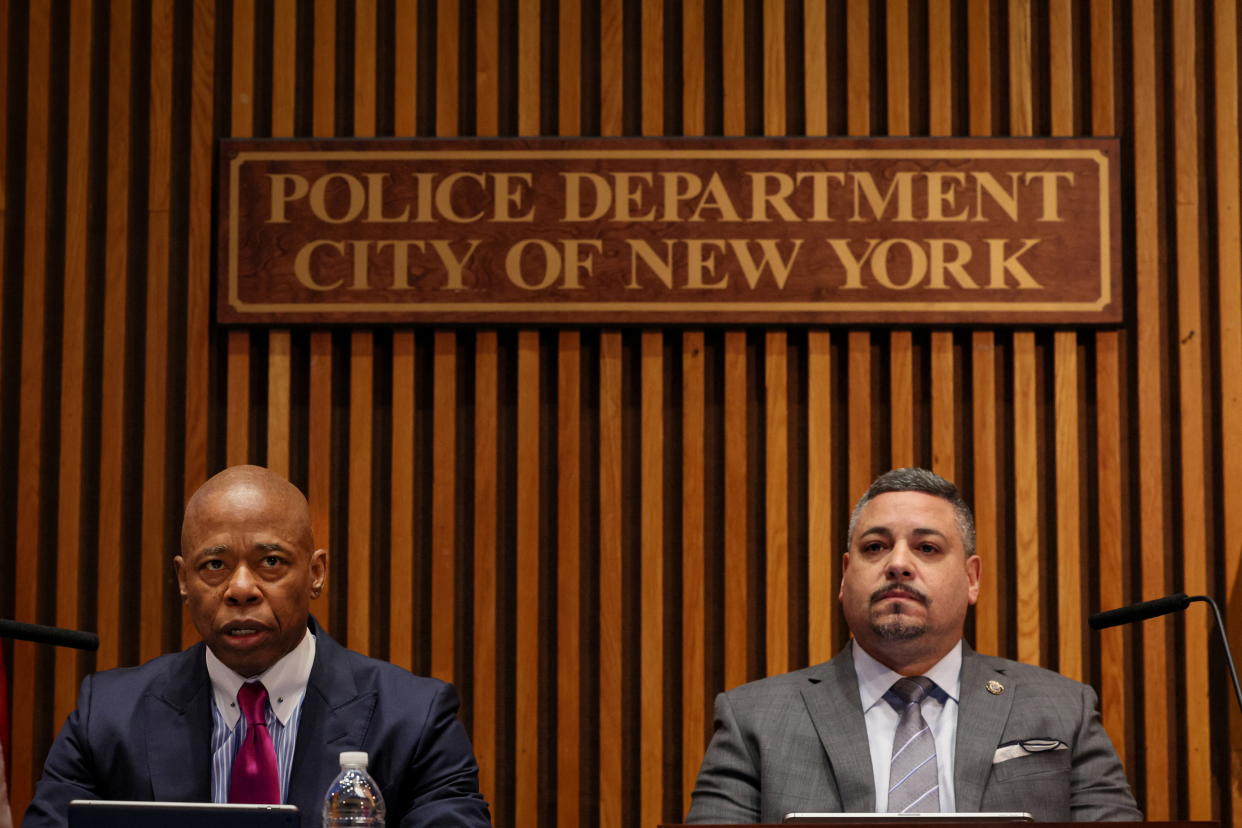 Adams and Caban sit at microphones beneath a sign that reads: Police Department, City of New York.