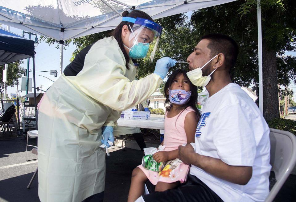 Jaylah Cisneros, 5, watches as registered nurse Katrina Nguyen with Community Medical Centers performs a COVID-19 test July 3 on Juan Cisneros at a site in Lodi, California.