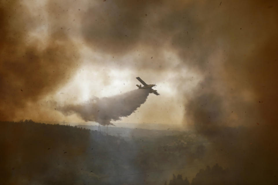 A firefighting airplane drops its load on a forest fire raging in the village of Casal da Quinta, outside Leiria, central Portugal, Tuesday, July 12, 2022. Hundreds of firefighters in Portugal continue to battle fires in the center of the country that forced the evacuation of dozens of people from their homes mostly in villages around Santarem, Leiria and Pombal. (AP Photo/Joao Henriques)