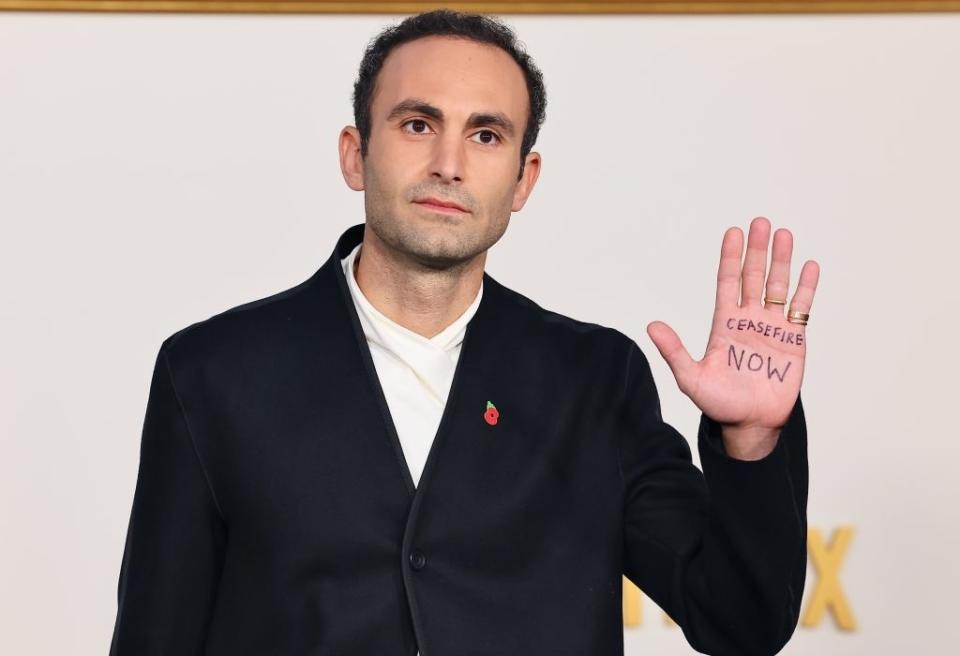 Khalid on the red carpet showing his palm with text that reads, "ceasefire now"