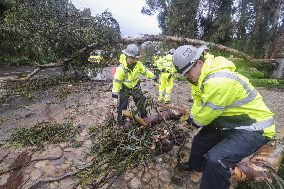 Firefighters clear away a fallen tree in Montecito, Calif., Tuesday, Jan. 10, 2023. California saw little relief from drenching rains Tuesday as the latest in a relentless string of storms swamped roads, turned rivers into gushing flood zones and forced thousands of people to flee from towns with histories of deadly mudslides. (AP Photo/Ringo H.W. Chiu)