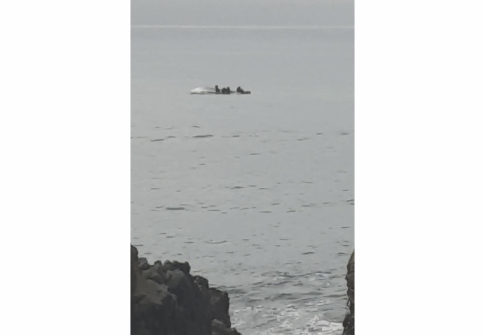 In this image taken from video, survivors cling to the upturned hull of a boat that capsized off the coast of Kaikoura, New Zealand, Saturday, Sept. 10, 2022. The boat had collided with a whale and capsized. (AP Photo)