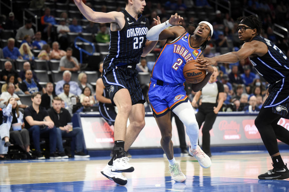 Oklahoma City Thunder guard Shai Gilgeous-Alexander, middle, tries to get past Orlando Magic forward Franz Wagner, left, and Wendell Carter Jr., right, in the second half of an NBA basketball game, Tuesday, Nov. 1, 2022, in Oklahoma City. (AP Photo/Kyle Phillips)