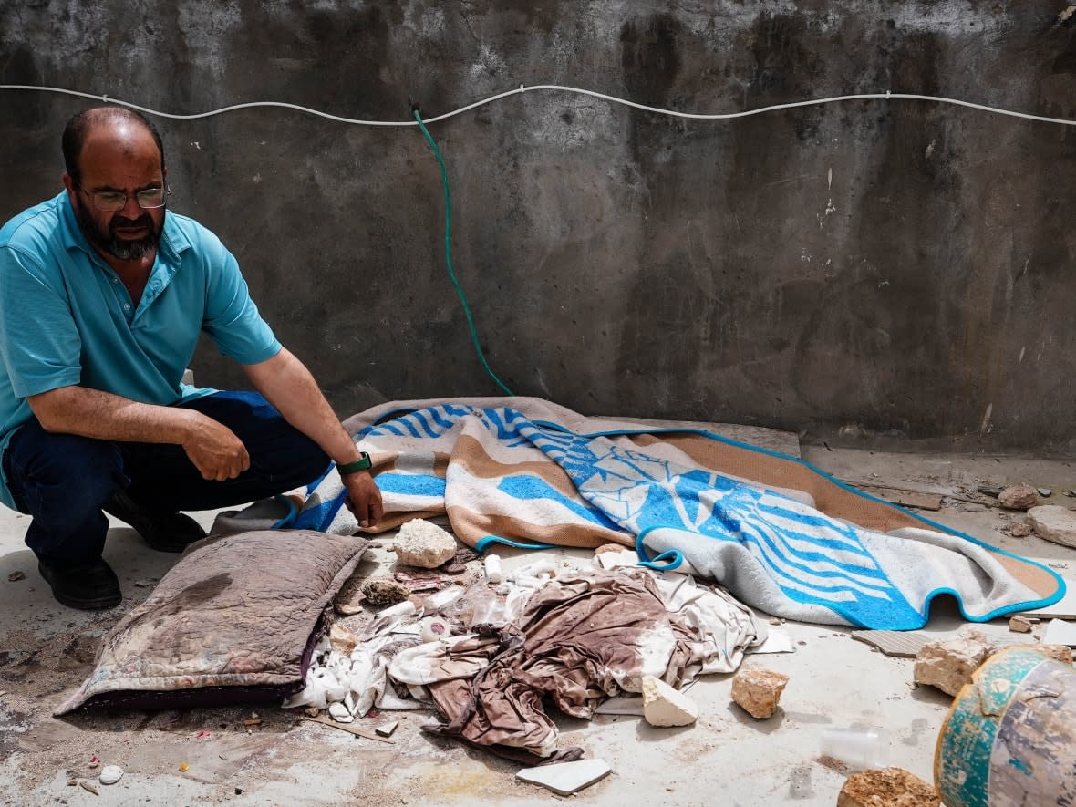 Abdullatif Abu Alia kneels over a pillow soaked with dried blood from where he said   his cousin, 25-year-old Jehad Abu Alia, bled to death after being shot in the head after his property was besieged on April 12 by Israeli settlers in the village of Al Mughayyir in the occupied West Bank. (Lily Martin/CBC - image credit)