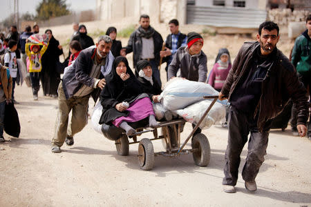 A man pulls a cart with a woman sitting on it as people flee the rebel-held town of Hammouriyeh, in the village of Beit Sawa, eastern Ghouta, Syria March 15, 2018. REUTERS/Omar Sanadiki