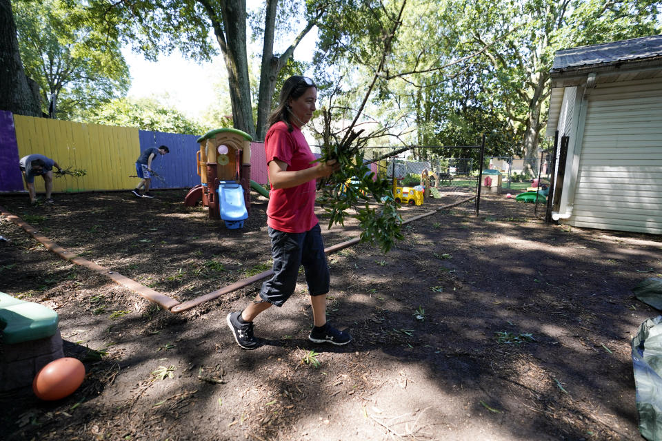 Mindy Wike, assistant director for Planet Playschool, cleans up branches surrounding her daycare following a storm that hit her town, Tuesday, Aug. 8, 2023, in Mooresville, N.C. (AP Photo/Erik Verduzco)