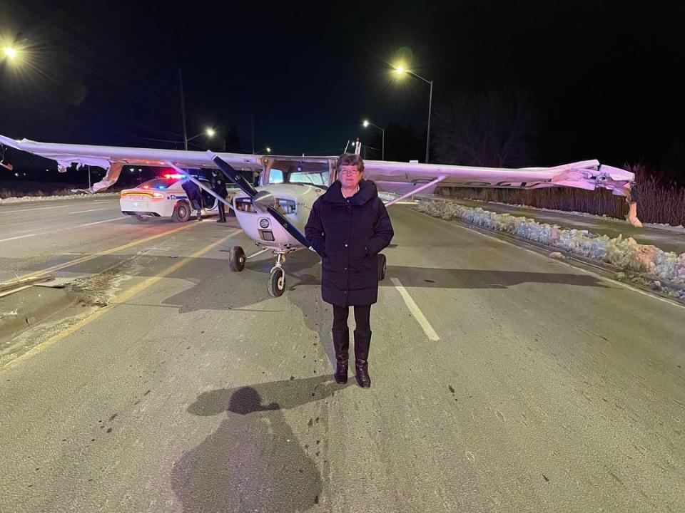 Debbie Gilker, a Durham Region resident, poses in front of a small plane that made an emergency landing in Ajax on Monday night.