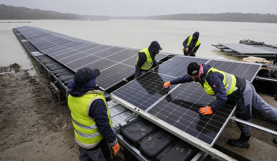 Solar panels are installed at a floating photovoltaic plant on a lake in Haltern, Germany, Friday, April 1, 2022. Once completed, around 5,800 photovoltaic modules will produce around 3 million kilowatt hours of electricity per year, saving 1,100 tons of CO2 to fight climate change with renewable power instead of oil, gas and coal. (AP Photo/Martin Meissner)