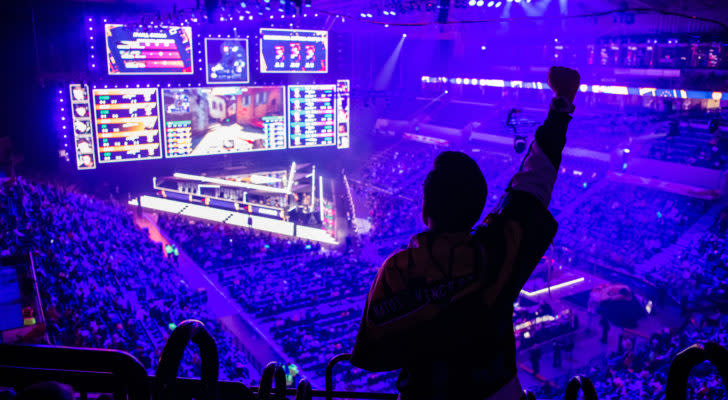 a fan holding up their hand in a live, esports arena. MGAM stock