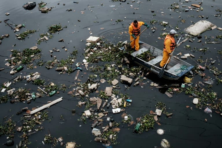 Cleaners clear up debris caught by the "eco-barrier" at Guanabara Bay near to Rio de Janeiro, Brazil, on July 20, 2016