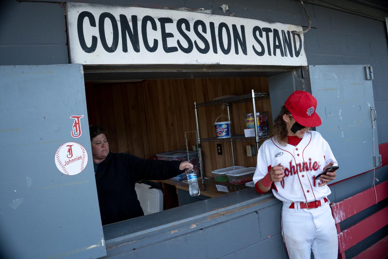 Angela Myers hands Johnstown’s Kaden Carpenter a water from behind the concession stand during a baseball game between Johnstown and Columbus Academy at Johnstown-Monroe High School. A new law requires at least one concession stand accept cash.
