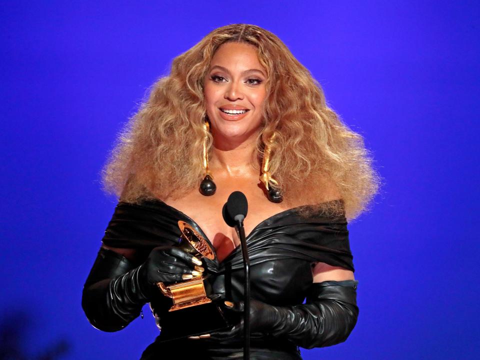 Beyonce with blonde curly hair and holding an award.