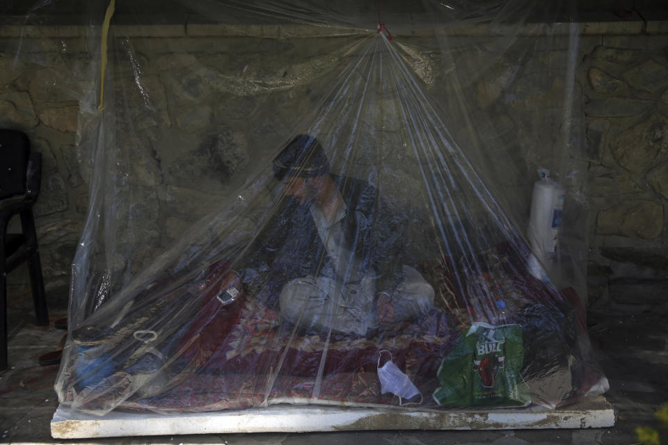 In this Monday, May 18, 2020 photo, a relative of a patient covers himself with a plastic sheet as he waits for his relative outside the Afghan-Japan Communicable Disease Hospital, Kabul’s main facility for coronavirus testing and treatment, in Kabul, Afghanistan. After 20 years and billions of dollars in international money, much of it from the U.S., the Afghan capital hardly has a hospital that works, with coronavirus tests lost, misread and misunderstood. (AP Photo/Rahmat Gul)