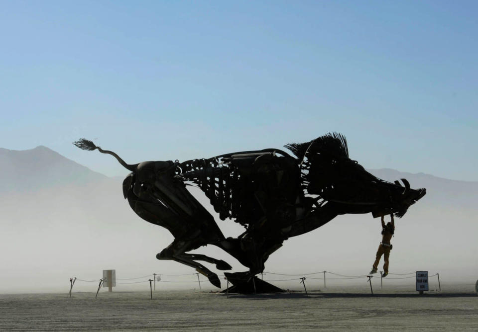 <p>Burners play on an interactive wild boar sculpture on a dusty morning at Burning Man in the Black Rock Desert near Gerlach, Nev. on Saturday, Aug. 27, 2016. The annual festival is dedicated to community, art, self-expression and self-reliance. (Andy Barron /The Reno Gazette-Journal via AP)</p>