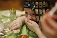 Rayna Segal, 8, puts her hand to her mouth reacts to the taste of the horseradish, a bitter herb, offered as part of the traditional Passover seder plate, during a virtual sedeer conducted by her father from their home which sometimes doubles as a synagogue, during the current coronavirus outbreak, Wednesday, April 8, 2020, in New York. According to tradition, all seder participants the bitter herb to help them recall bitter times Jews experienced under Egyptian bondage before fleeing Egypt for Israel. (AP Photo/Kathy Willens)