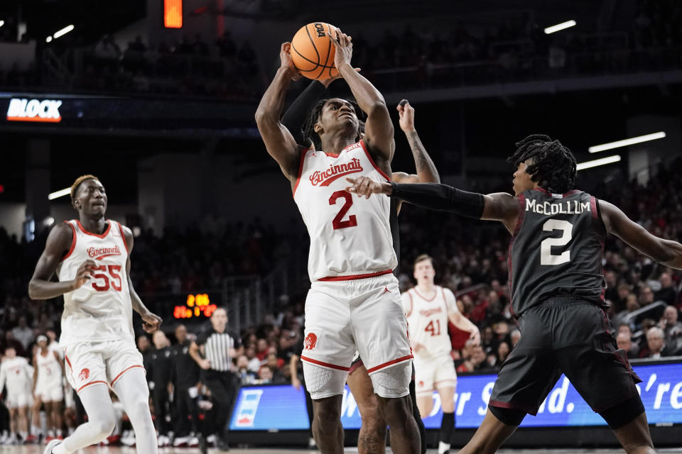 Cincinnati guard Jizzle James, center, attempts a shot as Oklahoma guard Javian McCollum, right, defends during the first half of an NCAA college basketball game, Saturday, Jan. 20, 2024, in Cincinnati. (AP Photo/Joshua A. Bickel)