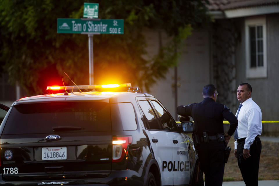 Ontario Police stand outside the scene where two children, an infant and a teenager, were found dead with their mother, who was unresponsive, at a home, Tuesday, Aug. 20, 2019, in Ontario, Calif. (Terry Pierson/The Orange County Register via AP)