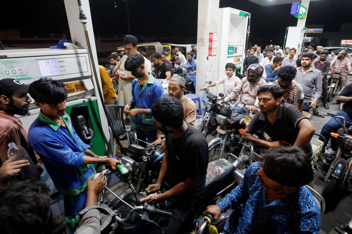 People wait their turn to get fuel at a petrol station, in Karachi (REUTERS)