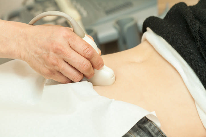 a closeup of a man performing an ultrasound on a woman's stomach area