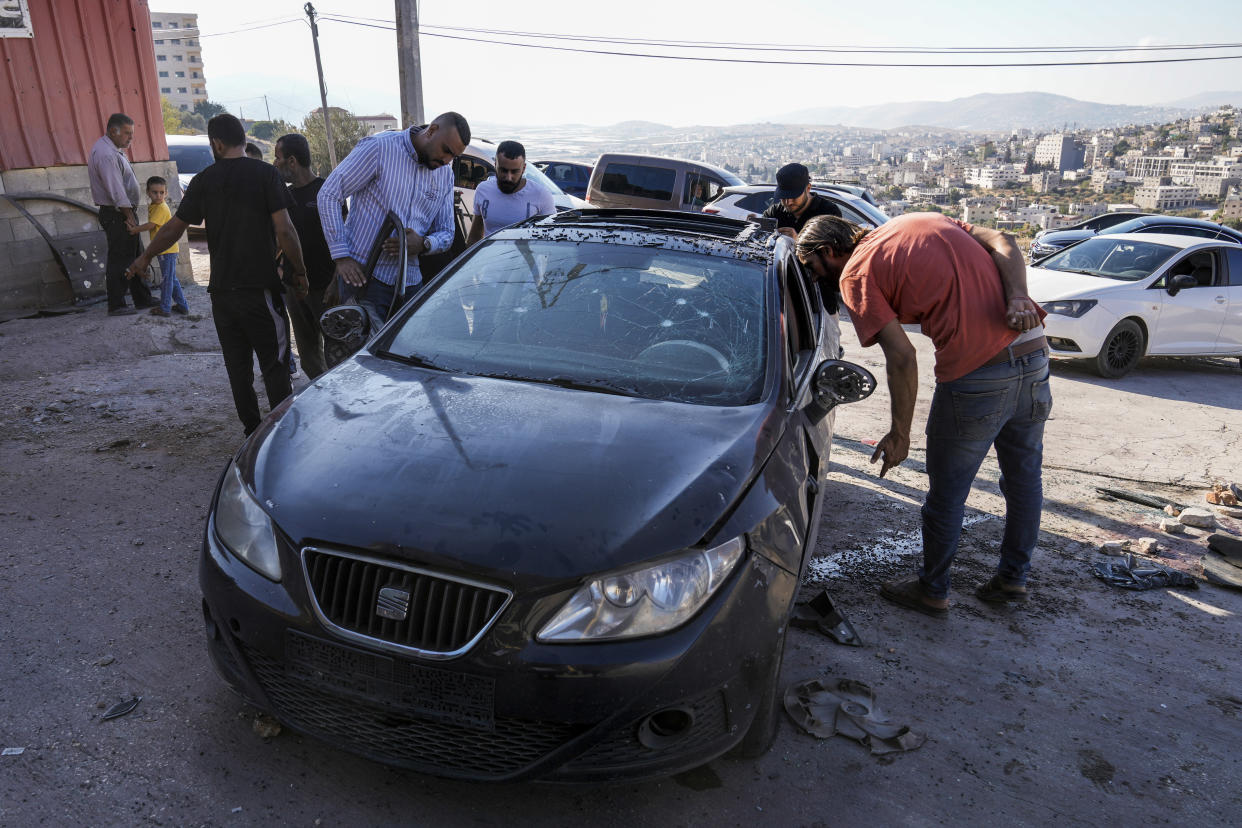 Palestinians look at a damaged car following an Israeli airstrike in Tubas, West Bank, Thursday, Sept. 5, 2024. Palestinian health officials say Israeli strikes in the occupied West Bank killed five people. Israel has been carrying out large-scale raids in the territory over the past week that it says are aimed at dismantling militant groups and preventing attacks. (AP Photo/Majdi Mohammed)