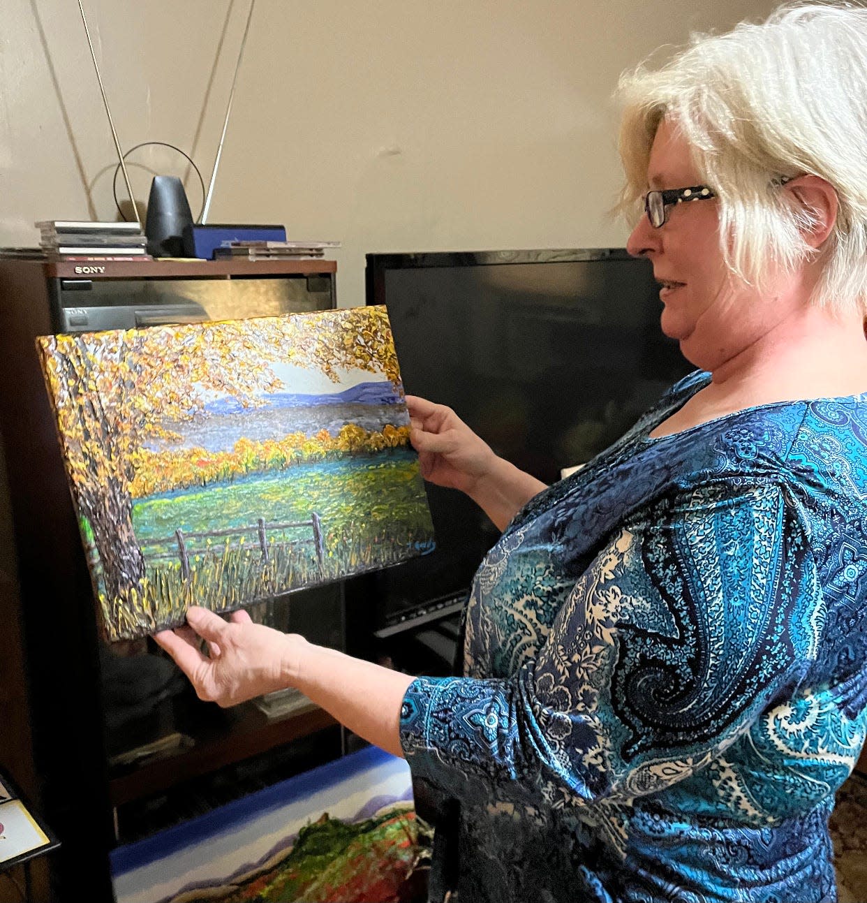 Terrie Gordy poses with one of her paintings.