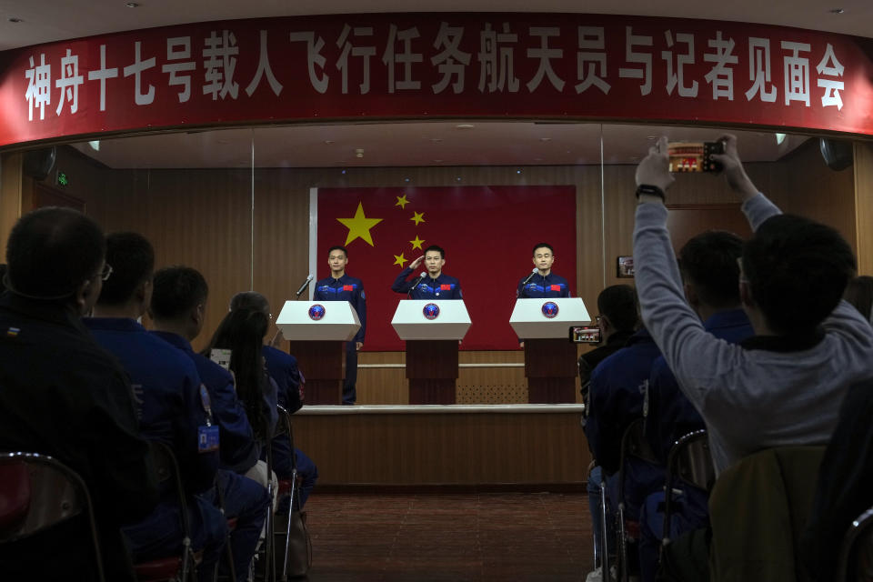 Tang Hongbo, a Chinese astronaut and commander for the upcoming Shenzhou-17 mission, center, salutes as he and his comrades Jiang Xinlin, left, and Tang Shengjie arrive for a meeting with the press at the Jiuquan Satellite Launch Center in northwest China, Wednesday, Oct. 25, 2023. (AP Photo/Andy Wong)