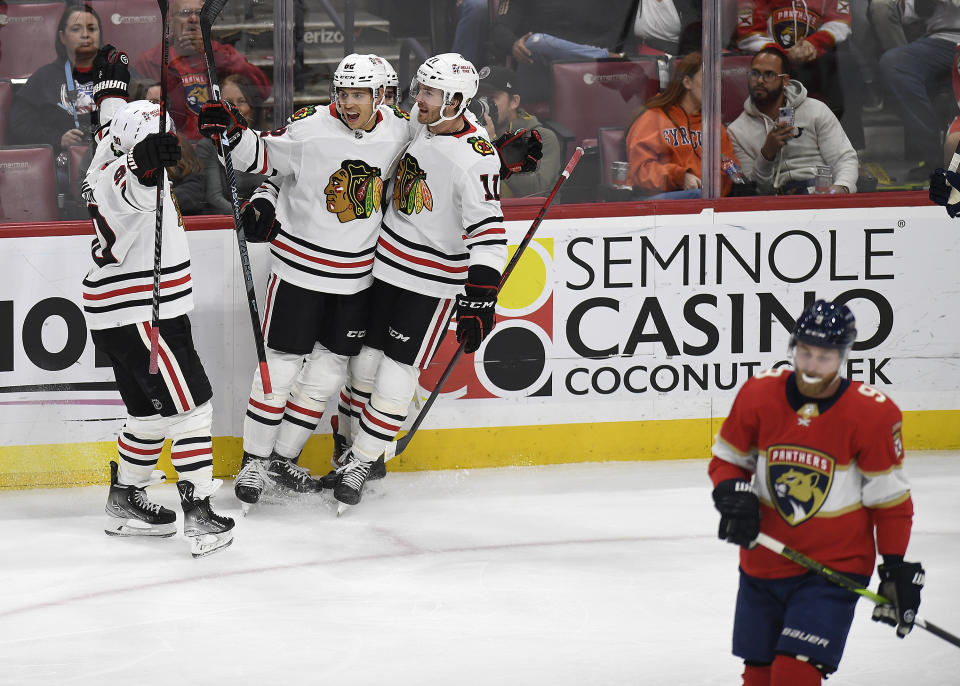 Chicago Blackhawks defenseman Caleb Jones (82), center, celebrates after scoring a goal against the Florida Panthers during the first period of an NHL hockey game, Friday, March 10, 2023, in Sunrise, Fla. (AP Photo/Michael Laughlin)