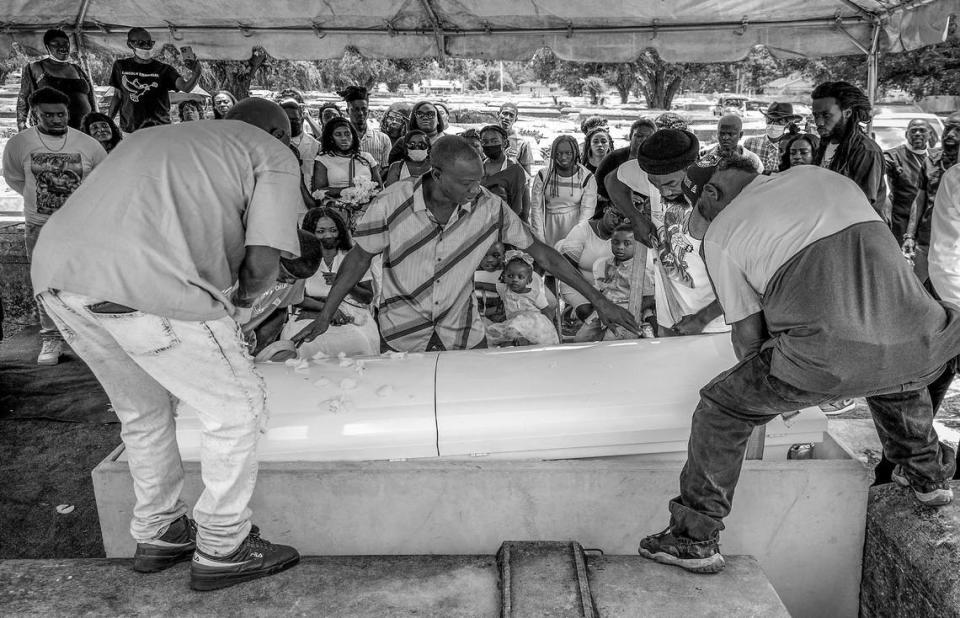 Jessie Wooden, center, assists his staff in positioning a casket as loved ones gather for a burial at Lincoln Memorial Park.