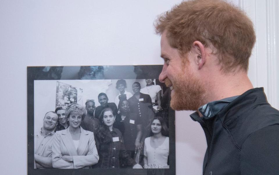 Prince Harry with a picture of his mother Princess Diana, with staff and users of The Running Charity, which is the UK's first running-orientated programme for homeless and vulnerable young people, in Willesden in north west London. - Credit: Geoff Pugh