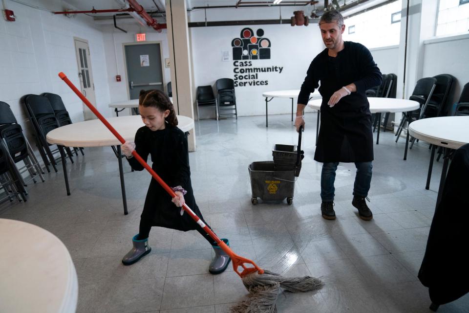 Mitzvah Day volunteer Naomi Wagner, 8, of Berkley, left, puts her heart into mopping as her dad Mitchell Wagner, 40 of Berkley wheels up the bucket in the dining area at the Cass Community Social Services in Detroit on Monday, Dec. 25, 2023. Volunteers from the Jewish and interfaith community volunteer to give the day off to employees so they can be home for Christmas.