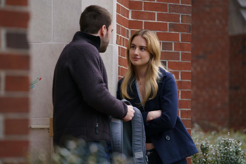 a young man and woman talking by a building