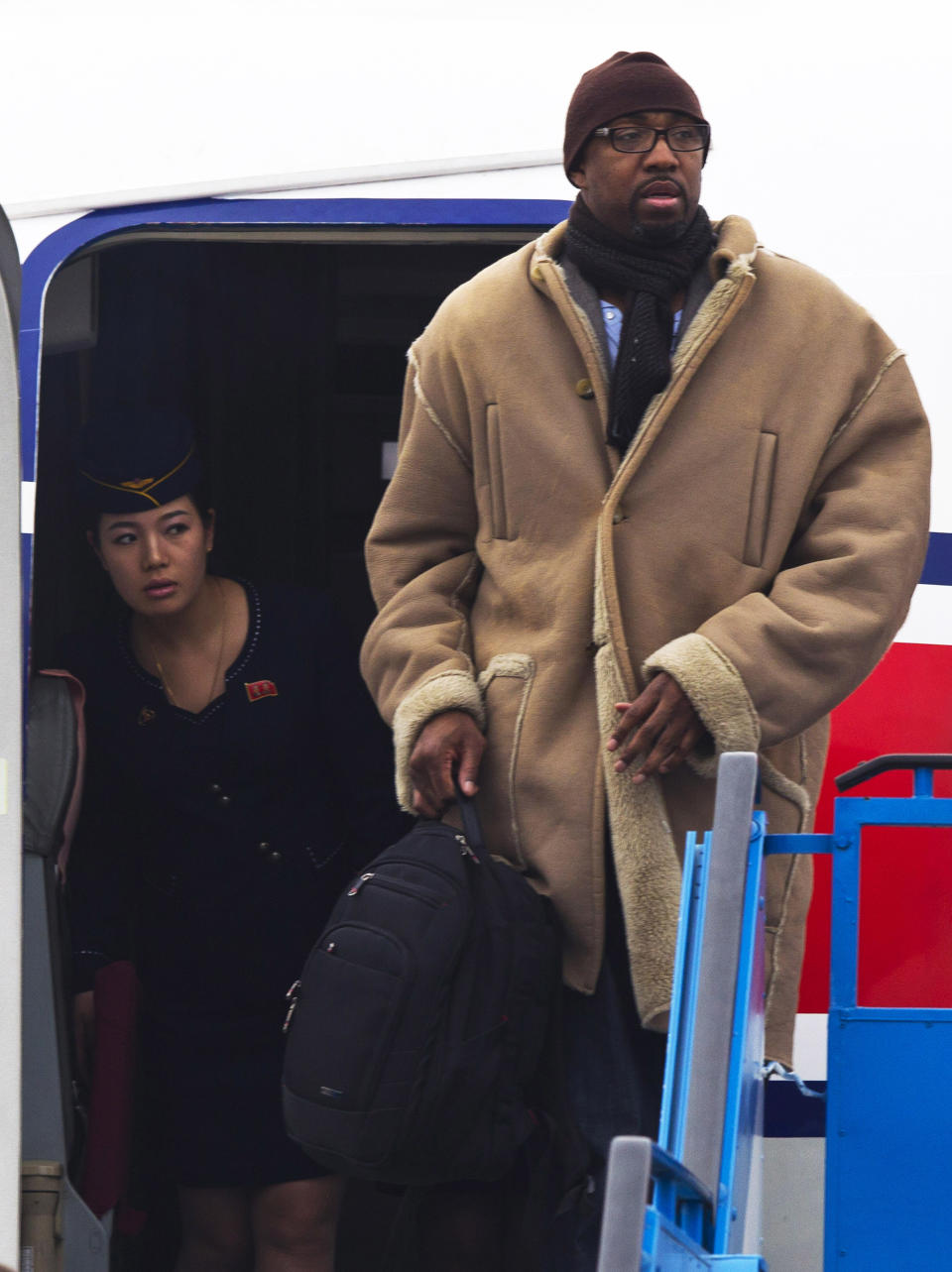 A North Korean Air Koryo flight attendant peeks out from the aircraft door as former NBA basketball player Vin Baker arrives at the international airport in Pyongyang, North Korea Monday, Jan. 6, 2014. Dennis Rodman arrived in the North Korean with a squad of former basketball stars including Baker in what Rodman calls "basketball diplomacy," although U.S. officials have criticized his efforts. (AP Photo/Kim Kwang Hyon)