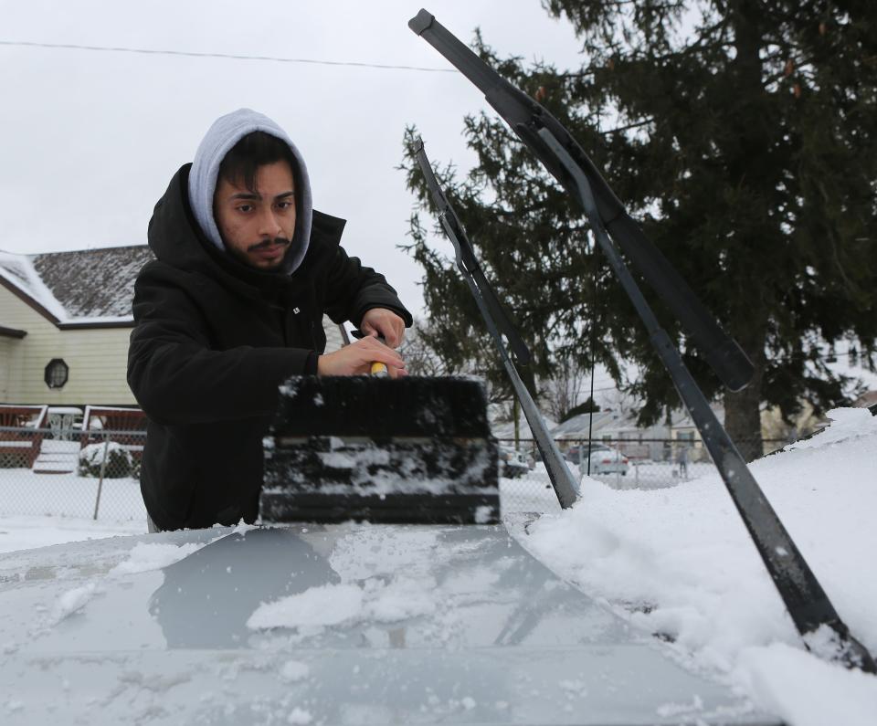 Arturo Mejia clears off his car on Monday, Feb. 1, 2021, after a nor'easter dumped snow, sleet and rain over much of Delaware.