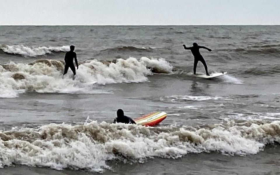 Three surfers, all dressed in wet suits, take on the waves at Presque Isle State Park's Beach 1 West on Dec. 7.