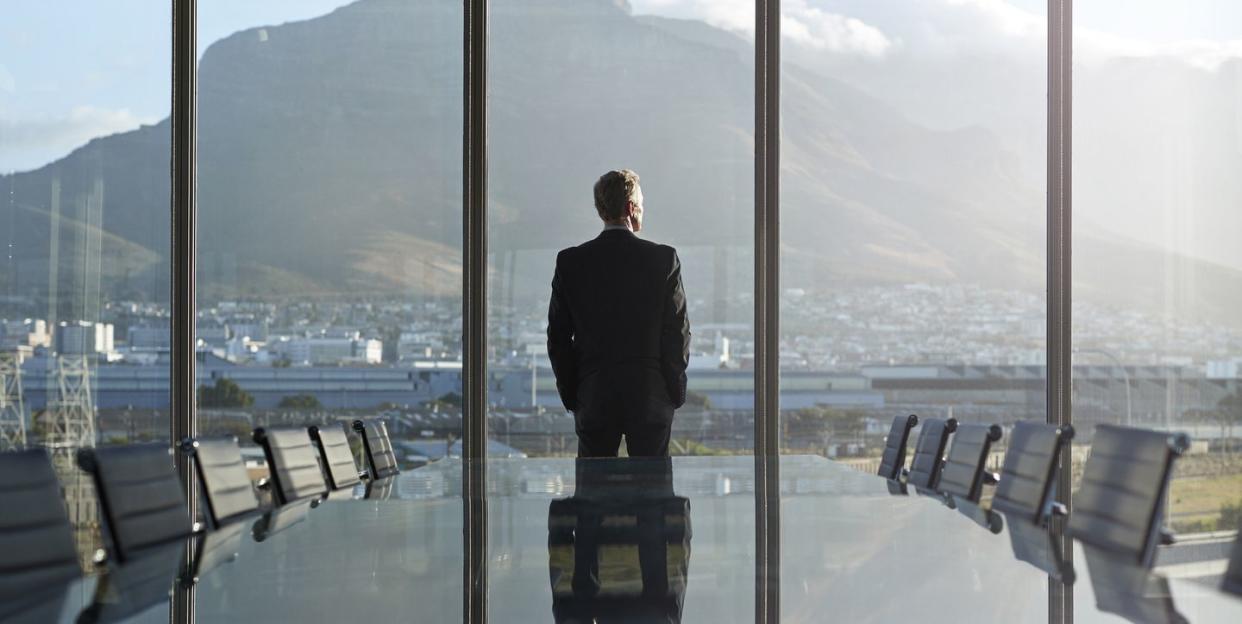 portrait of male ceo in big corner office, looking out of window