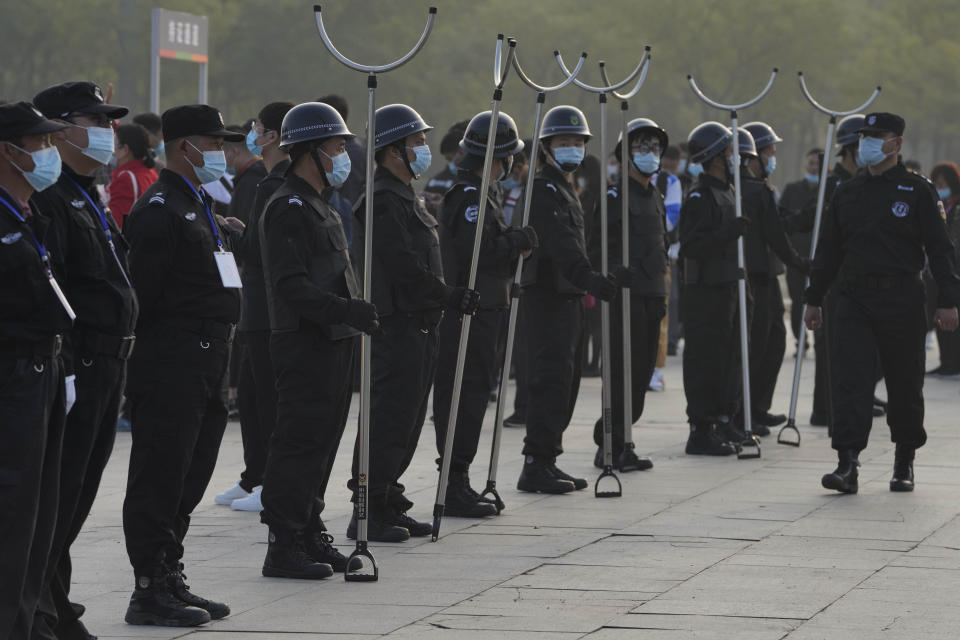 Security guards wearing masks and armed with restrainers stand guard at the entrance to the Auto China 2020 show in Beijing, China on Saturday, Sept. 26, 2020. The auto show, the first major in-person sales event for any industry since the coronavirus pandemic began, opens Saturday in a sign the ruling Communist Party is confident China has contained the disease. Still, automakers face intensive anti-virus controls including quarantines for visitors from abroad and curbs on crowd sizes at an event that usually is packed shoulder-to-shoulder with spectators. (AP Photo/Ng Han Guan)