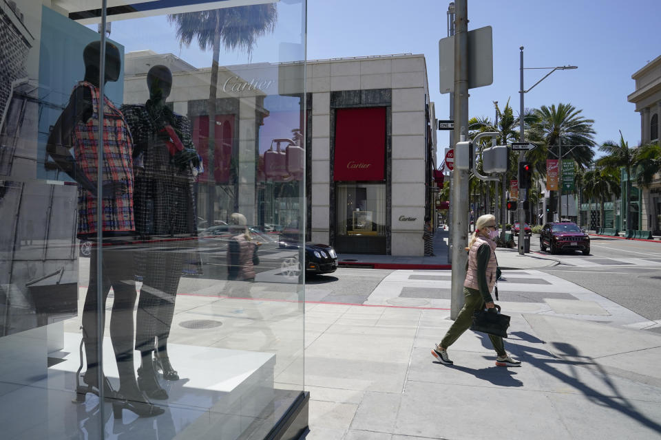 A woman wearing a face mask walks past a window display at Chanel on Rodeo Drive Tuesday, May 19, 2020, in Beverly Hills, Calif. (AP Photo/Ashley Landis)