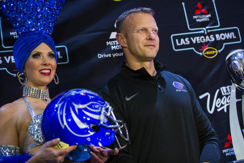 Boise State head coach Bryan Harsin poses alongside showgirl Jennifer Autry ahead of the Las Vegas Bowl NCAA college football game in Las Vegas, Tuesday, Dec. 17, 2019. (Chase Stevens/Las Vegas Review-Journal via AP)