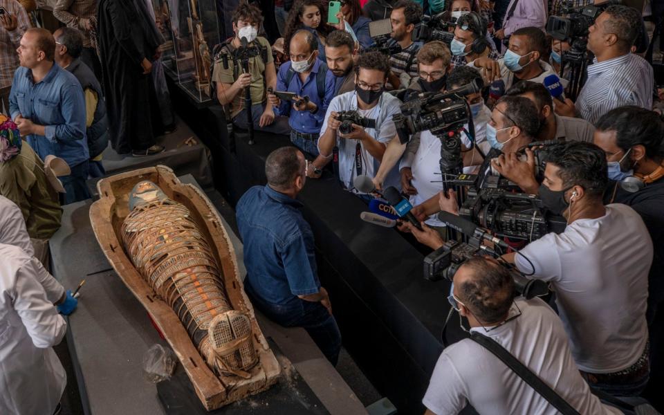 Journalists gather around an ancient sarcophagus more than 2500 years old, discovered in a vast necropolis and Mostafa Waziri - AP