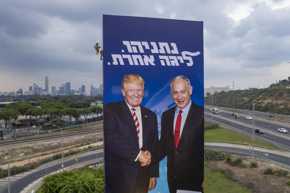 FILE - In this Sunday, Sept. 8, 2019 file photo, a worker hangs an election campaign billboard of the Likud party showing US President Donald Trump, left, and Israeli Prime Minister Benjamin Netanyahu in Tel Aviv. Israel is heading to an unprecedented repeat election next week with no guarantee that the do-over vote will produce a more decisive result than an inconclusive one last April. Hebrew on the billboard reads "Netanyahu, another league." (AP Photo/Oded Balilty, File)