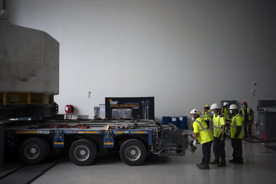 Workers receive a central solinoid magnet for the ITER project in Saint-Paul-Lez-Durance, France, Thursday, Sept. 9, 2021. Scientists at the International Thermonuclear Experimental Reactor in southern France took delivery of the first part of a massive magnet so strong its American manufacturer claims it can lift an aircraft carrier. (AP Photo/Daniel Cole)