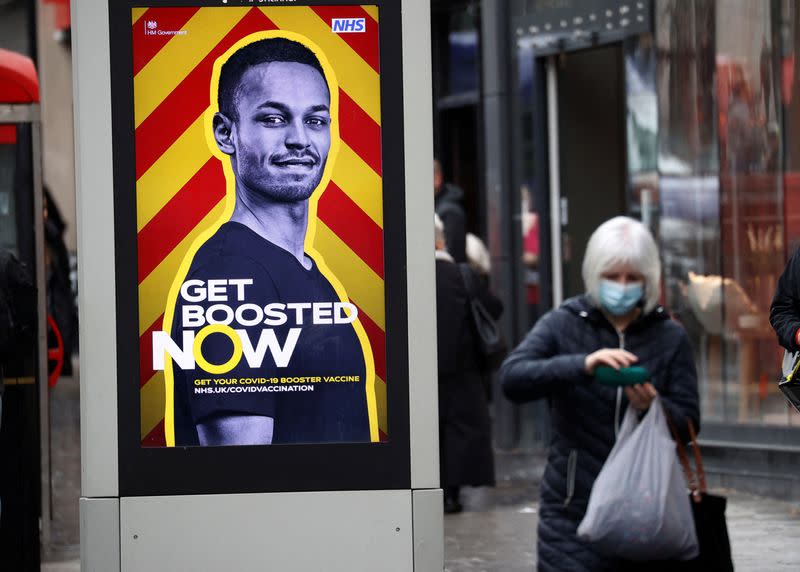 A woman walks past an advertising board encouraging people to get their booster vaccination, amid the coronavirus disease (COVID-19) outbreak in Liverpool